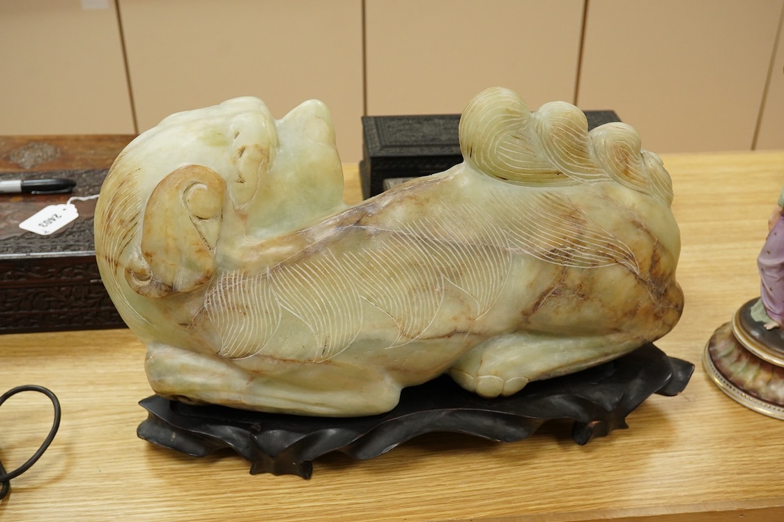 A large Chinese bowenite jade model of a lion dog, wood stand, 44cm